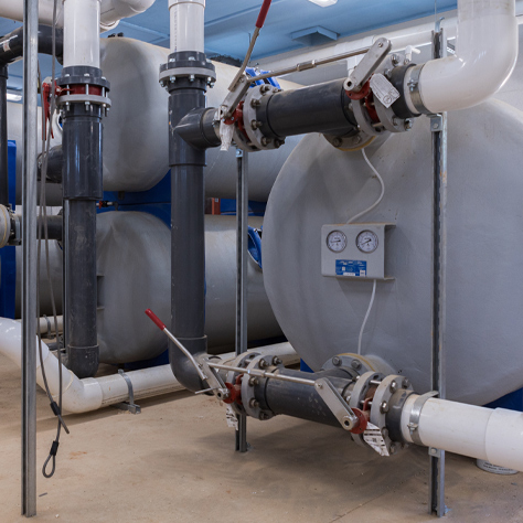 mermade-filter-fiberglass-commercial-pool-filter-in-operation-474-474 Pictured is a series of stacked and single fiberglass commercial pool filters in a pool filter room. Also shown are the face piping, plumbing and valves that are connected.