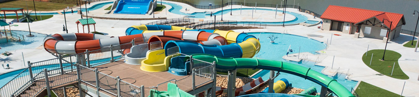 This images shows multicolored water slides in a waterpark with a pool in front that the slides empty into